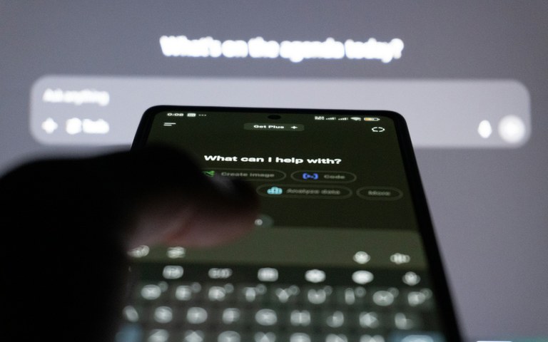 Nahaufnahme eines Smartphones mit geöffnetem KI-Chat vor einem unscharfen Bildschirm